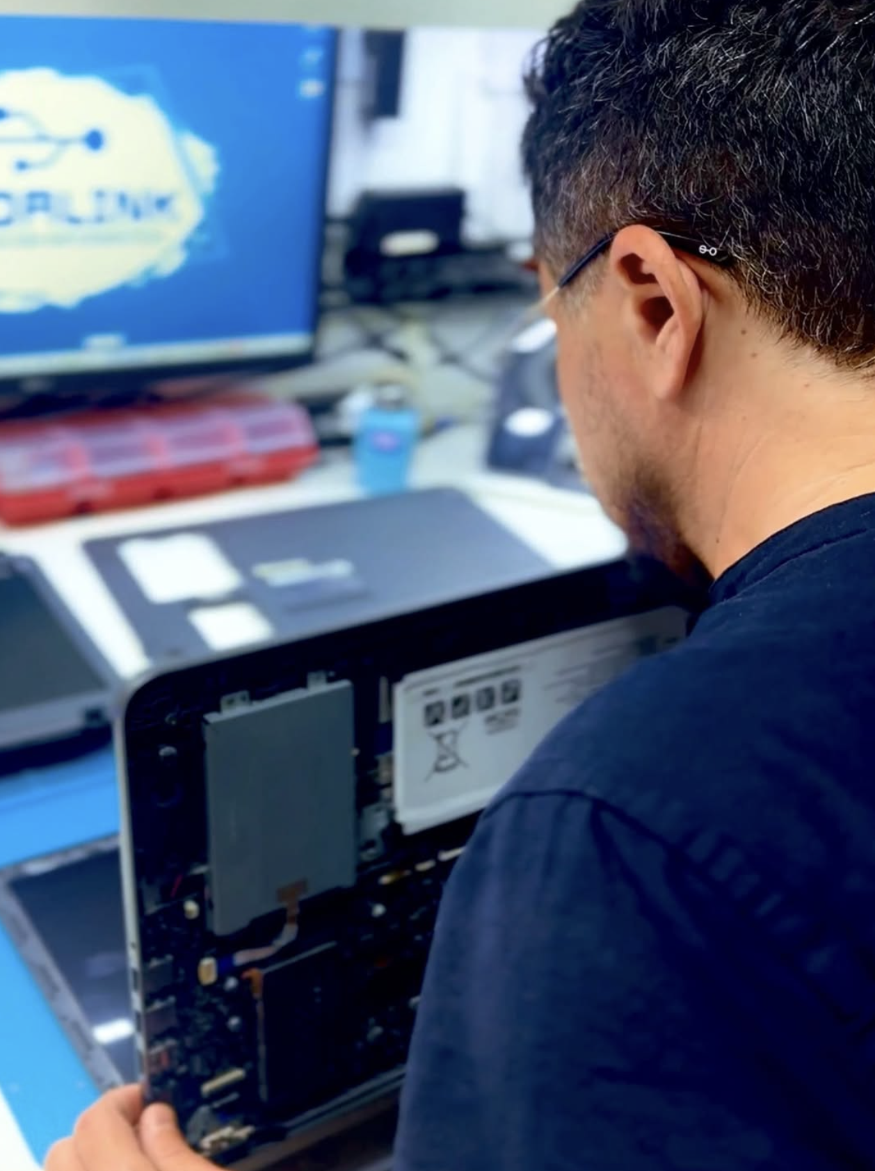 Técnico da Inforlink reparando a placa-mãe de um notebook em bancada